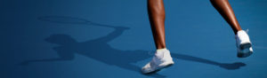 Image showing the legs of someone playing tennis on a blue tennis court.